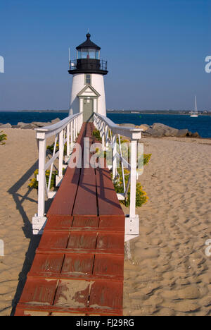Rustic old wooden walkway bridge to Brant Point lighthouse on Nantucket Island in Massachusetts appears to welcome visitors. It is a New England icon. Stock Photo