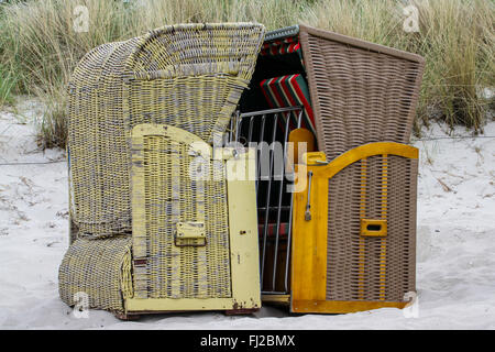 Two basket chairs facing each other on sandy beach Stock Photo