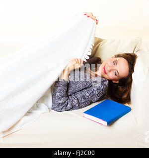 Health balance sleep deprivation concept. Sleeping woman on sofa. Girl lying on couch with book relaxed or taking power nap. Stock Photo