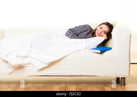 Health balance sleep deprivation concept. Sleeping woman on sofa. Girl lying on couch with book relaxed or taking power nap. Stock Photo