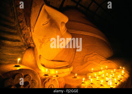 Candle offerings to 11th century reclining BUDDHA at SHINBINTHAHLYAUNG TEMPLE - BAGAN, MYANMAR Stock Photo