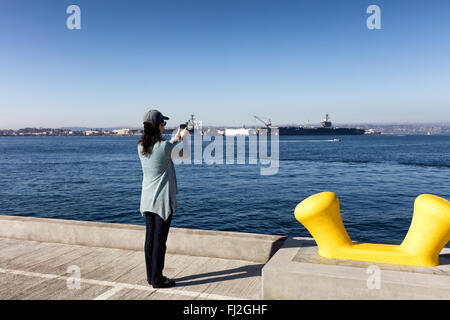 Back view of a woman taking photos with cell phone San Diego bay in Southern California. Stock Photo