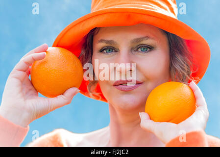 Woman in orange hat  holding a two oranges Stock Photo