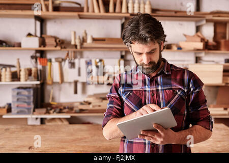 Woodwork designer using a digital tablet in his studio Stock Photo