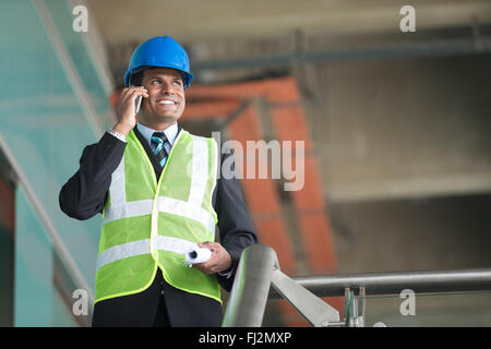 Portrait of a male Indian Architect or industrial engineer at work using phone. Stock Photo