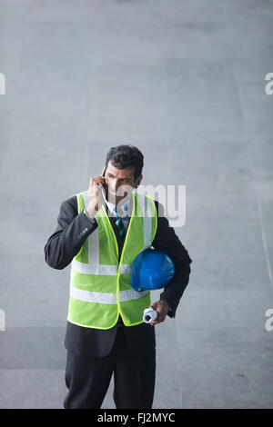 High angle view of an Indian Architect or industrial engineer at work using phone. Stock Photo