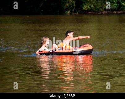 Two Boys Having Fun on Inflatable Rubber Boat in Summer Stock Photo