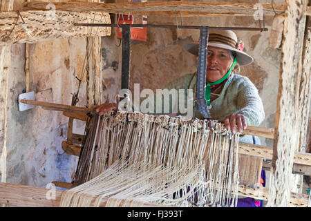 Indian woman weaving at a traditional weaving loom made out of cactus wood, Argentina Stock Photo