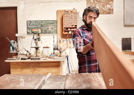 Carpenter expertly checking a wooden plank for straightness and Stock Photo
