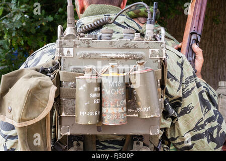 War and Peace show, England. Vietnam war re-enactment. American field radio with three smoke canisters, two red, one yellow, on back, plus field pack. Stock Photo
