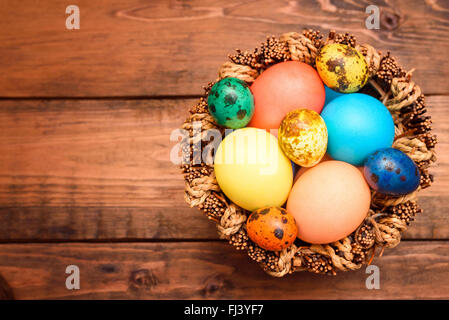 Traditional  easter eggs in wicker basket on the wooden table. top view Stock Photo