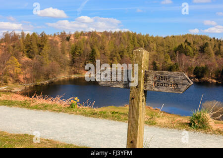 Old wooden public footpath signpost on path around Tarn Hows SSSI in Lake District National Park. Coniston, Cumbria, England, UK Stock Photo