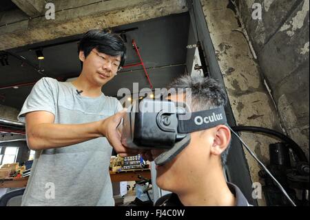 Beijing, China. 29th February, 2016. The young maker Hou Xiaoye (L) wears a  head-mounted display for an experiencer in Changchun, northeast China's Jilin Province, July 30, 2015.    By encouraging mass entrepreneurship and innovation, China saw a record startup boom in 2015 as a total of 4.44 million companies were established, up 21.6 percent from a year ago. More than 80 percent of the new firms were in tertiary industries.     The boom came after government efforts to encourage people to open their own businesses, including easier market entry, less red tape and tax breaks. Stock Photo