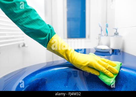 Hand in yellow glove washes sink. Stock Photo