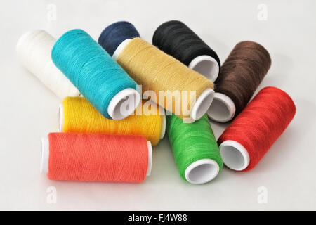 Spools of threads of different colors on light table Stock Photo