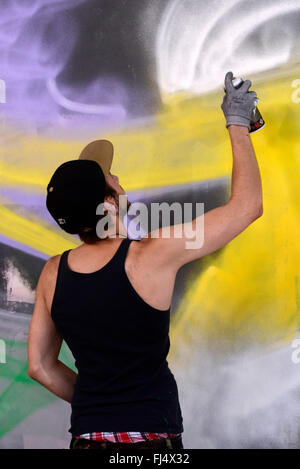 man spraying graffiti at a wall in an abandonend industrial ground, Germany, North Rhine-Westphalia, Duesseldorf Stock Photo