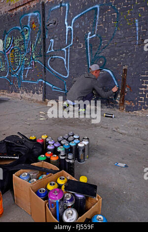 man spraying graffiti at a wall in an abandonend industrial ground, Germany, North Rhine-Westphalia, Duesseldorf Stock Photo