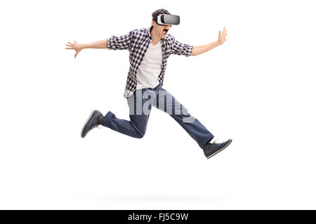 Excited young man experiencing virtual reality through a VR headset shot in mid-air isolated on white background Stock Photo