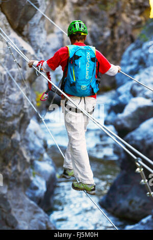 climber crossing the canyon on a suspension bridge, France, Hautes Alpes, Chateau Queyras Stock Photo