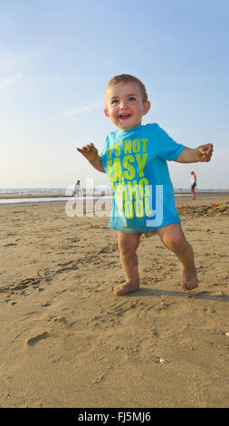 little laughing boy wearing a T-shirt on a sandy beach, Netherlands