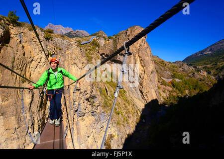 man on suspension footbridge crossing the Durance river, France, Hautes Alpes Stock Photo