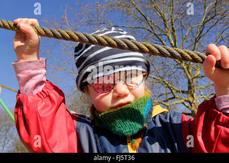 little girl with glasses and an eye patch holding on a rope, Germany Stock Photo