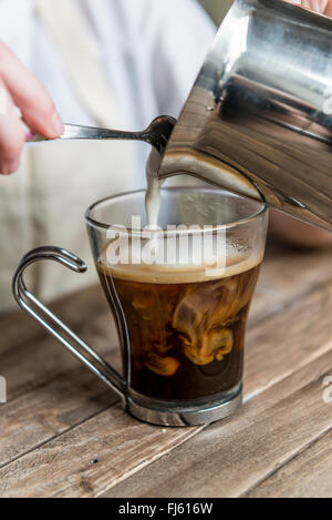 A black coffee. Milk being poured in to a coffee by a barista. Stock Photo