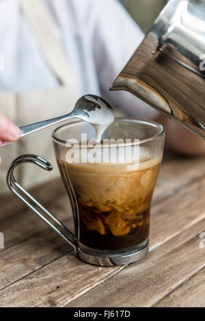 A black coffee. Milk being poured in to a coffee by a barista. Stock Photo