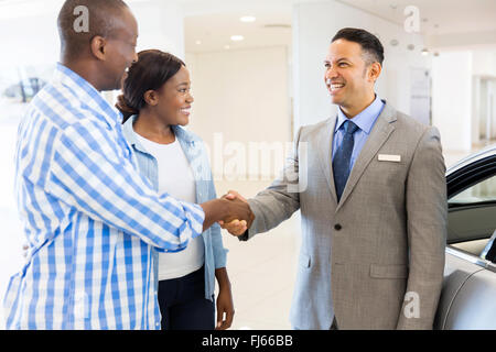 middle aged salesman handshaking with happy African couple Stock Photo