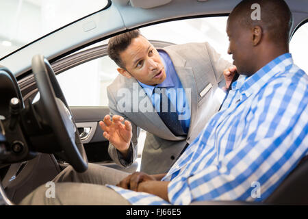 friendly salesman explaining car features to customer Stock Photo