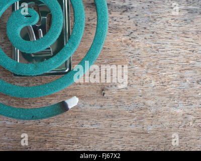 the Mosquito repellent incense lit on the old wooden floor with the dead Mosquito as the blurred background Stock Photo