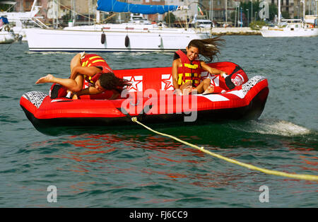two girls are be pulled over the water with an air couch, France, Corsica Stock Photo