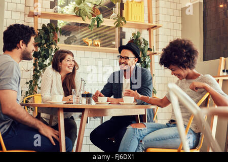 Group of friends enjoying in cafe together. Young people meeting in a cafe. Young men and women sitting at cafe table and smilin Stock Photo