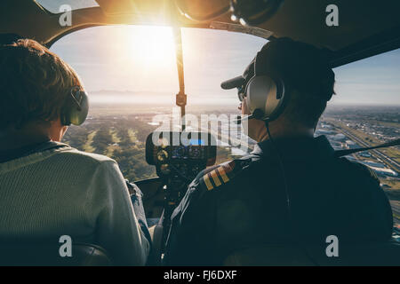 Inside view of a helicopter in flight, with man and woman pilots flying a helicopter on a sunny day. Stock Photo