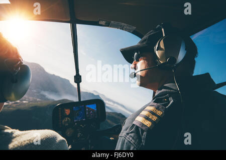 Man and woman pilots flying a helicopter on a sunny day. Inside shot of a helicopter. Stock Photo