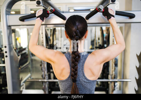 Woman in gym flexing back muscles on cable machine Stock Photo