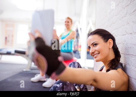Fit woman in gym holding smart phone, taking selfie Stock Photo