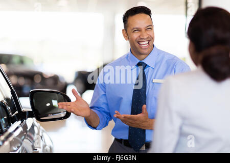 friendly vehicle dealer showing young woman new car Stock Photo