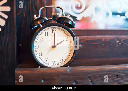 Old alarm clock standing on a wooden surface in the background mirror Stock Photo