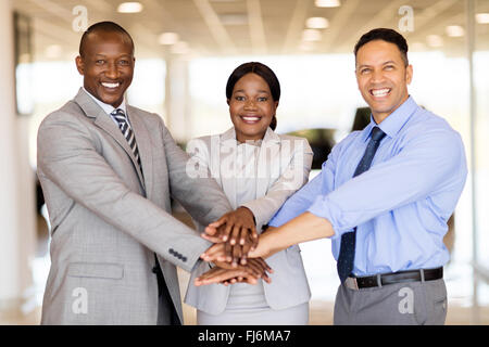 happy vehicle sales team putting their hands together inside showroom Stock Photo