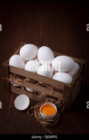 Bunch of fresh white eggs in a wooden crate on a brown background Stock Photo