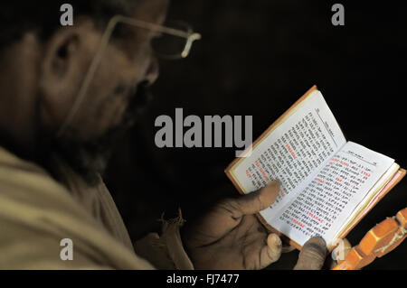 Orthodox priest reads Holy Scriptures inside Mikael Milhaizengi rock-hewn church in the Tigray Region, Ethiopia Stock Photo