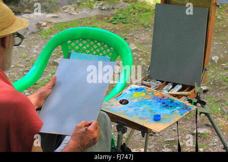 The elderly artist drawing on fresh air, in nature's lap Stock Photo