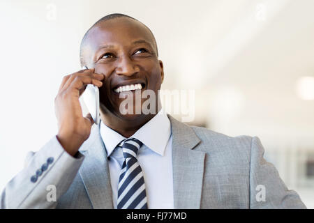 cheerful black businessman talking on smart phone in office Stock Photo