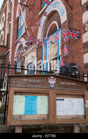 Town council noticeboard and Pickering & District Conservative Club exterior, decked with Union Jack bunting - Pickering, North Yorkshire, England. Stock Photo