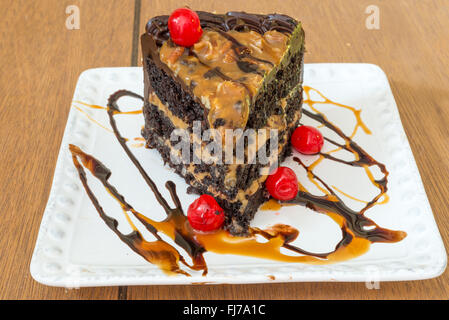 Delicious chocolate caramel cake with almonds and red cherries Stock Photo