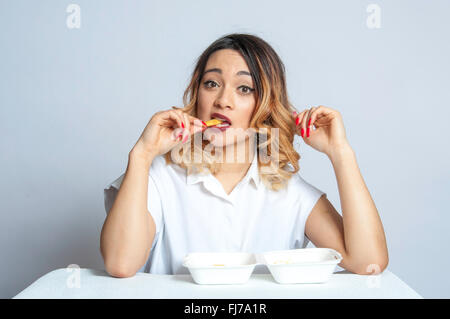 Young British Asian girl eating chips in studio setting, London, England, United Kingdom Stock Photo