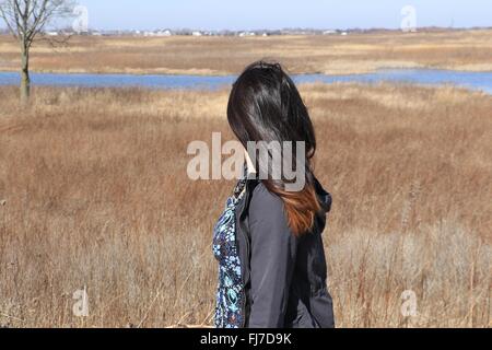 Teenage Asian girl stares off in a prairie, wind blowing in her hair. Stock Photo