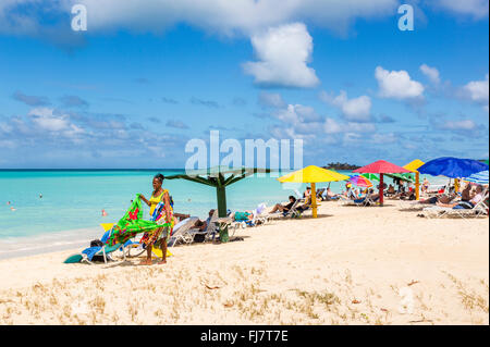 Local woman selling colourful scarves, wraps, sarongs and towels on the beach in Runaway Bay, north Antigua, Antigua and Barbuda Stock Photo