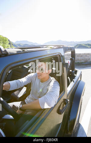 Happy young Chinese man driving a jeep Stock Photo